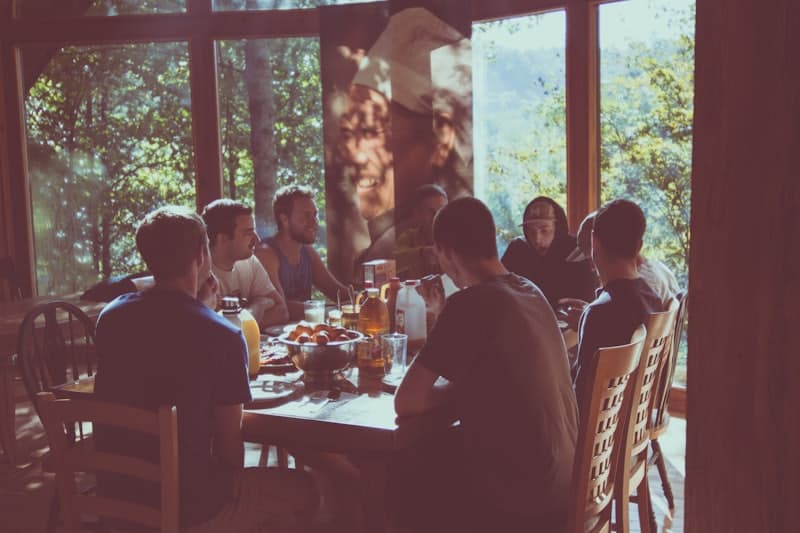 Friends around a dinner table by a big window